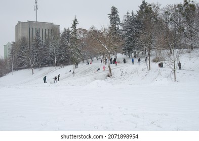 Lutsk, Ukraine - January 14 2020. Winter Fun. People Are Sledding From Slide In City Park. Parents And Children Enjoy Winter. Fun On The Snow In The City.