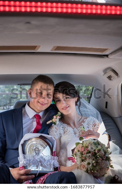 Lutsk. Ukraine. July 2,\
2017; The bride and groom drink wine from glasses in the salon of a\
wedding car