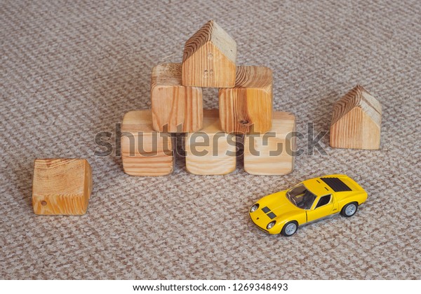 Lutsk, Ukraine - November 26th, 2018: Wooden\
building blocks for kids. Toy building made of wooden cubes. Toy\
car model among wooden\
cubes	