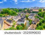 Luxembourg City historical centre aerial panoramic view, old buildings and green trees in river Alzette valley, Luxembourg cityscape with blue sky, panorama of Luxembourg old town Grund district