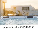 Luxurious bath on top of residential building with open space terrace, scenic view, sunlight. Hot tub with hydromassage jet on roof at sunset. Bath on rooftop of luxury hotel. Spa treatment concept