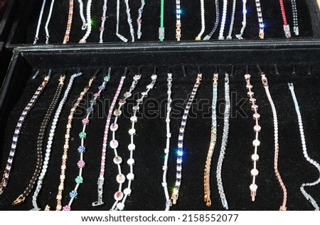 luxurious bracelets and necklaces made of precious stones and silver or white gold for sale by the jeweler in the velvety black tray
