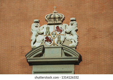 Luxurious Carved Decoration With Coat Of Arms From Spanish Royalty On Bricks Wall Facade, In A Sunny Day At Madrid. Capital Of Spain This Charming Metropolis Has Vibrant And Intense Cultural Life.