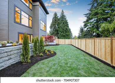 Luxurious contemporary three-story wood siding home exterior in Bellevue. Nice backyard landscape with well kept lawn, flower beds and wooden fence. Northwest, USA - Shutterstock ID 704907307