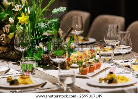 Luxurious dining table setup featuring gourmet appetizers, elegant glassware, floral centerpiece, and sophisticated decor, ideal for upscale events, weddings, banquets, and exclusive dinner parties.