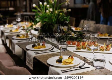 Luxurious dining table setup featuring gourmet appetizers, elegant glassware, floral centerpiece, and sophisticated decor, ideal for upscale events, weddings, banquets, and exclusive dinner parties.