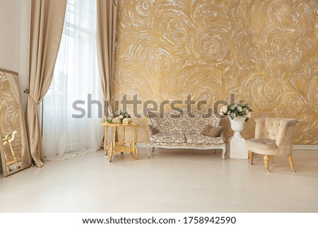 
luxurious expensive interior of a large baroque royal living room. antique furniture, gold trim, huge windows, fireplace with gold stucco on the walls. full of daylight