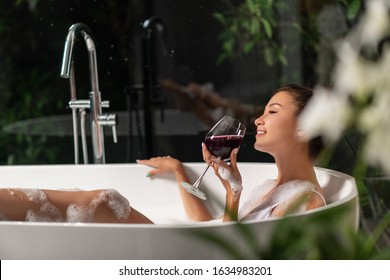 A Luxurious Girl Is Relaxing In A Bubble Bath With A Glass Of Wine. Spa And Relaxation