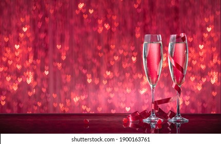 Luxurious glasses with sparkling wine on a mirror surface on a red shining bokeh in shape of a heart background. Valentine's day or romantic evening invitation - Powered by Shutterstock