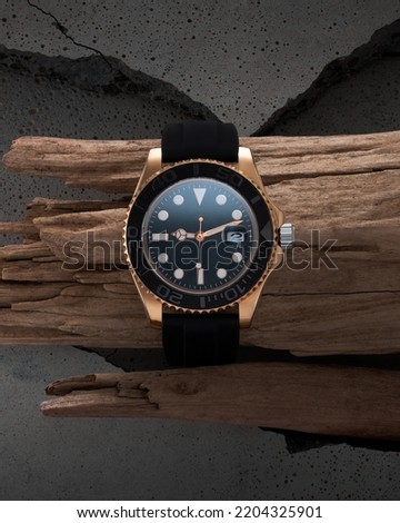 Luxurious golden watch. Black strap watch on a beautiful piece of wood, advertising of a watch for men and women.
