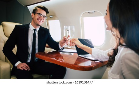 Luxurious Life. Close-up Photo Of A Successful Man, Who Is Clinking With His Flute Of Champagne With His Colleague, While Taking A Flight On The Board Of A Business Class Plane.