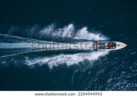 Luxurious  motor boat rushes through the waves of the blue Sea. Boat fast moving aerial view. Luxurious boat fast movement on dark water.