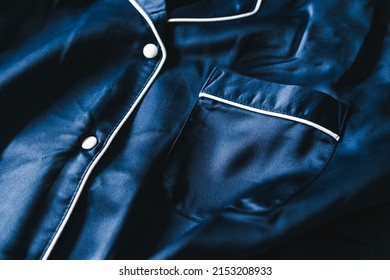 luxurious navy blue silk or satin tailored pyjama detail, fabric close-up with soft wrinkles and light shining on it 
