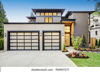 Luxurious New Construction Home In Bellevue, WA. Modern Style Home Boasts Two Car Garage Spaces With Glass Folding Doors Illuminated By Scones. Northwest, USA