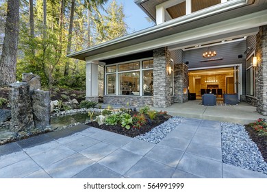 Luxurious new construction home exterior with front patio and perfect landscape design: nice garden pond with stone fountains. Northwest, USA
