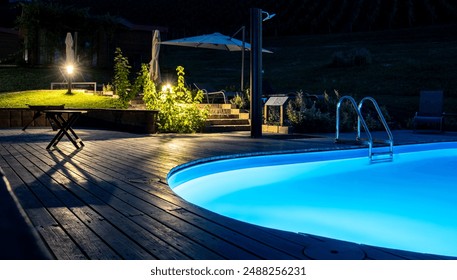 Luxurious nighttime outdoor setting featuring a brilliantly lit pool with LED lights creating a serene blue glow, surrounded by an illuminated garden and cozy poolside essentials. - Powered by Shutterstock