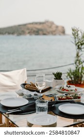 A luxurious oceanfront dining experience featuring a scenic view of the sea, elegant table setup, and gourmet cuisine. Perfect setting for a relaxing and sophisticated meal by the water in Greece