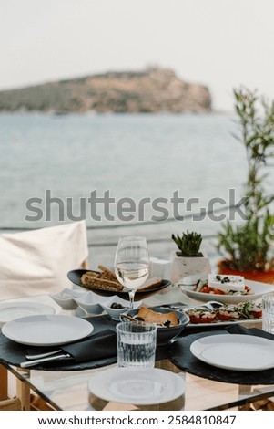 A luxurious oceanfront dining experience featuring a scenic view of the sea, elegant table setup, and gourmet cuisine. Perfect setting for a relaxing and sophisticated meal by the water in Greece