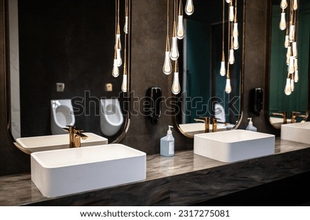 Luxurious public bathroom interior with sinks and mirrors and subdued lighting.