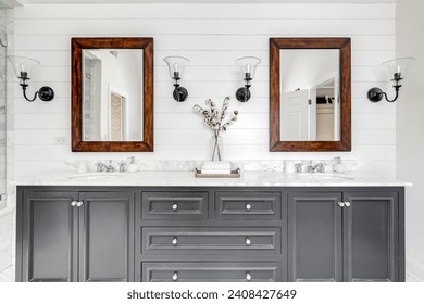 Un lujoso cuarto de baño reformado con lavabo gris, espejos enmarcados de madera rústica, pared de escopetas y grifería cromada.