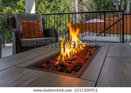 A luxurious spacious deck with stylish patio furniture  with a close up shot of a fire pit table heater