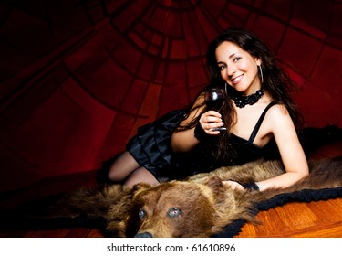 Luxurious Young Brunette Woman Drinking Vine On The Bear Skin Rug