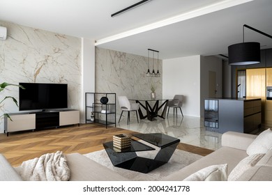 Luxury Apartment With Living Room With Big Tv Screen Open To Dining Room With Modern Table And Stylish Black And Gold Kitchen