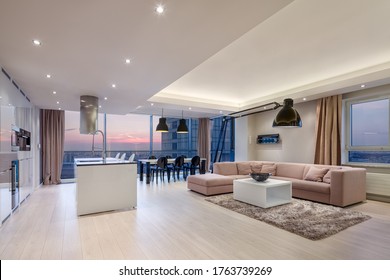 Luxury Apartment With Stylish Living Room, Kitchen And Dining Area And Big Windows During Sunset