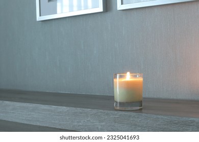  luxury aromatic scented candle glass is displayed on wooden table in the bedroom to create relax and romantic ambient on happy valentine day with background of nice wooden wall and phto frames