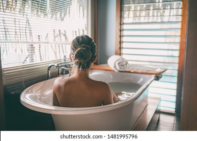 Luxury bath woman wellness spa relaxing soaking in warm water bathtub of hotel suite.