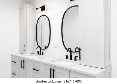 A luxury bathroom with a grey double vanity cabinet, black faucets and lights, and a white marble countertop.