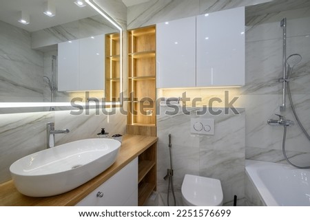 Luxury bathroom interior with marble tiles on the walls and a large mirror