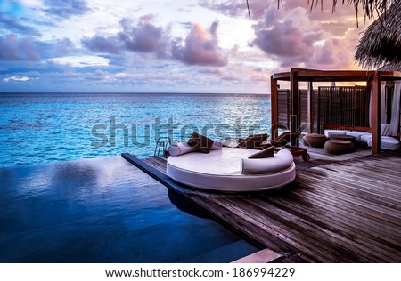 Luxury beach resort, bungalow near endless pool over sea sunset, evening on tropical island, summer vacation concept