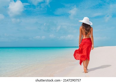 Luxury beach vacation elegant tourist woman walking relaxing in red beachwear and sunhat on white sand Caribbean beach. Lady tourist on holiday vacation resort - Shutterstock ID 2147290757