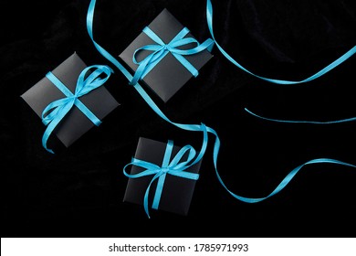 Luxury black gift boxes with blue ribbon on shine black background. Christmas, birthday party presents. Father Day. Flat lay. Copy space. Top view.