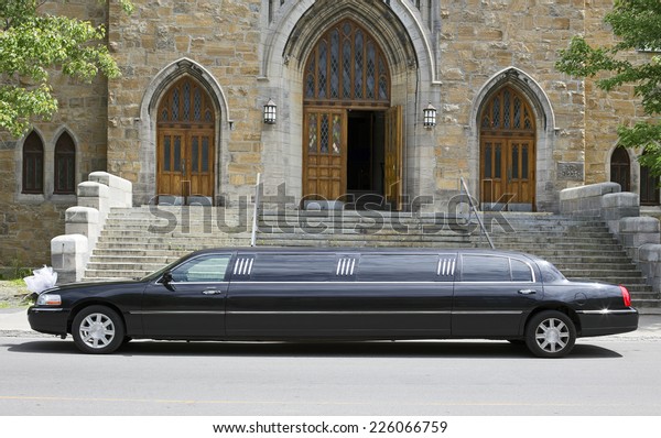 Luxury\
black limousine awaiting in front of a\
church