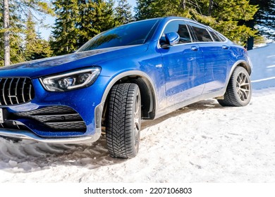 Luxury Blue Sedan Car Headlight Parked Outdoors On Snow In Cold Winter Day.Modern Automobile.vehicle In Bed Weather Conditions,adventure Extreme Sport,Carpathians Mountains,Ukraine,15 March 2022.