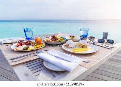 Luxury breakfast food on wooden table, with beautiful tropical Maldives island background, morning time holiday vacation concept.