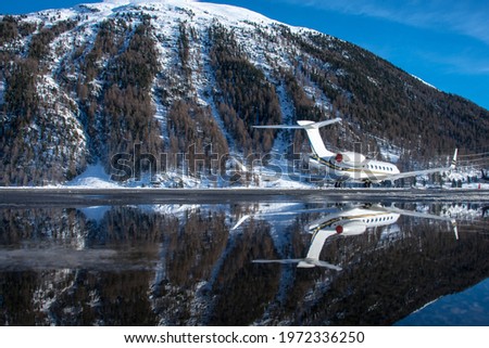 luxury business jet parked at Samedan airport. Successful business people use this airport to land at for their winter vaction in the Swiss alps. The water puddle is reflecting the plane and scenery.
