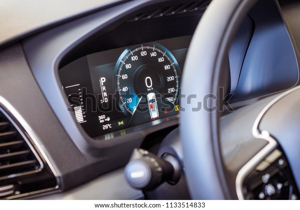Luxury car interior\
details. Dashboard and steering wheel. Modern car illuminated\
dashboard close-up. Speedometer. Speed control. Digital screen of\
telling speed of the\
car.