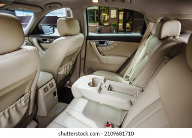 Luxury car interior made of white leather. Leather folding armrest armrest with cup holders in rear seats inside a vehicle. Clean leather interior: white rear seats, headrests and belts. - Shutterstock ID 2109681710