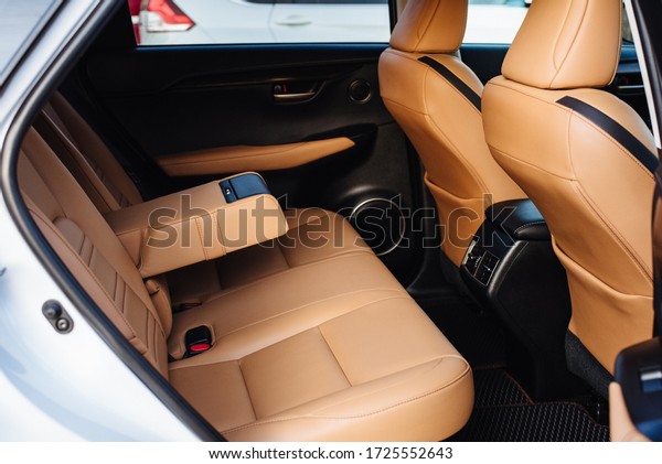 Luxury car interior made of yellow leather.
Leather folding armrest armrest with cup holders in rear seats
inside a vehicle. Clean leather interior: yellow rear seats,
headrests and belts.