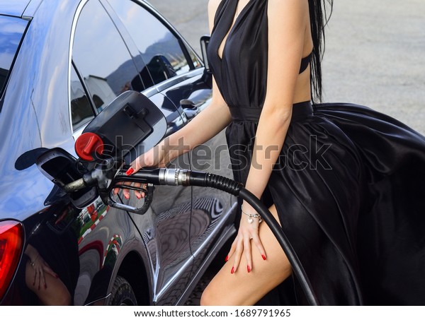 Luxury car. Petrol is for rich. Female filling\
car with gasoline. Gas station. Woman at gas station. Gas and\
diesel fuel. Transport and transportation. Petrol filling station.\
Oil products.