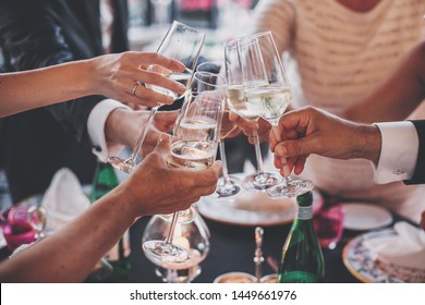 Luxury christmas celebration. People hands toasting with champagne glasses at delicious feast outdoors in the evening. Family and friends clinking glasses and cheering with alcohol