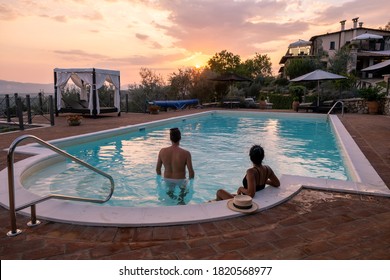 Luxury Country House With Swimming Pool In Italy. Pool And Old Farm House During Sunset Central Italy. Couple On Vacation At Luxury Villa In Italy, Men And Woman Watching Sunset