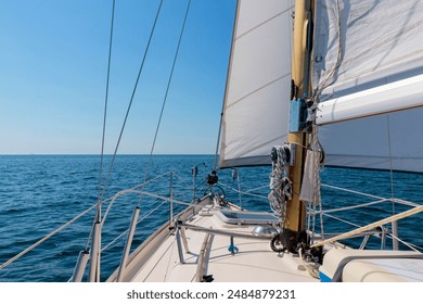 Luxury cruise on a sailing rigged yacht under a genoa and mainsail sailing in a light wind during the regatta. Yachting as a luxury sport and great vacation. View from the deck to the bow, mast, sails