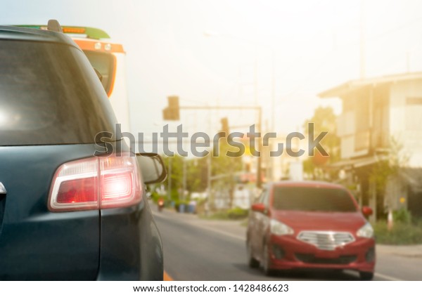 Luxury of dark green car\
stop on the asphalt junction by traffic light control in across.\
Open light during the bright period. Cars that run past from the\
opposite side.