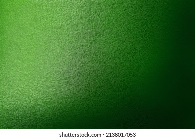 luxury dark green leather texture background showing grain and a shaft of light across. gradient green artificial leatherette texture use as background, close up view, with blank space for design.