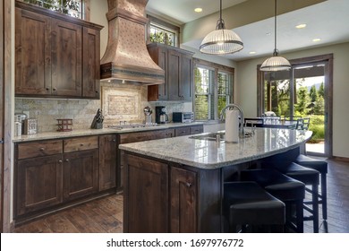 Luxury Dark Wood Rich Kitchen Interior With Copper Stove Hood And Grey Natural Stone Backsplash.