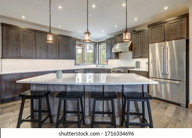 Luxury Dark Wood Rich Kitchen Interior With White Subway Tiles Backsplash And Quarts Countertop.